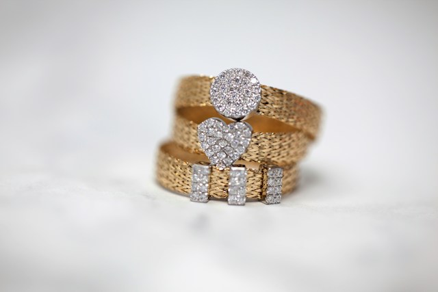 Three rings with thick gold bands and diamonds in the center stacked on top of each other.