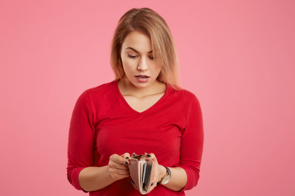 Woman with a surprised look on her face looking into an empty wallet